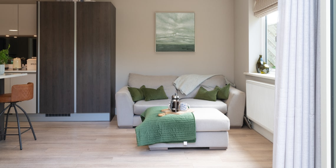 Fabric Sofa and Footstool next to Open Plan Kitchen